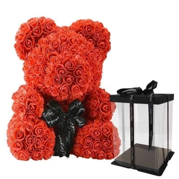 Red rose teddy bear with a black ribbon beside a clear gift box