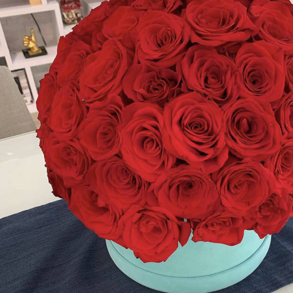 Red roses arranged in a round turquoise box