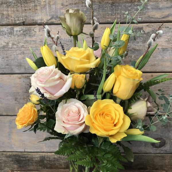 Yellow and pale pink roses arranged in a glass vase