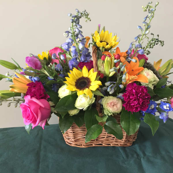 Colorful mixed flower basket with sunflowers, roses, lilies, and blue spikes