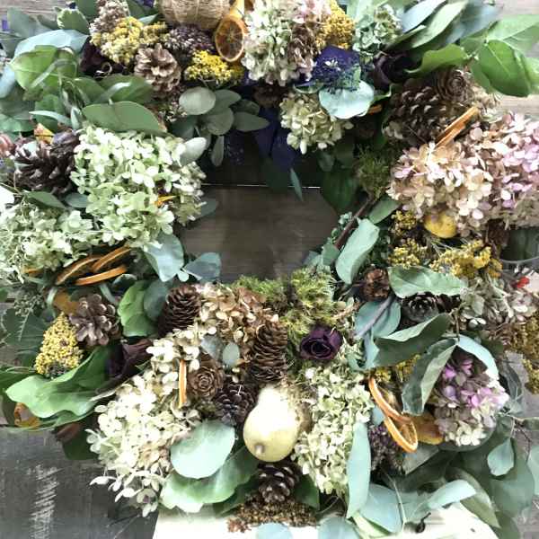 Large wreath with dried flowers, pinecones, and eucalyptus on a wooden background