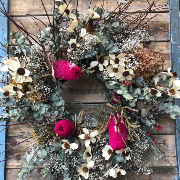 Floral wreath with cream flowers and pink accents on a wooden background