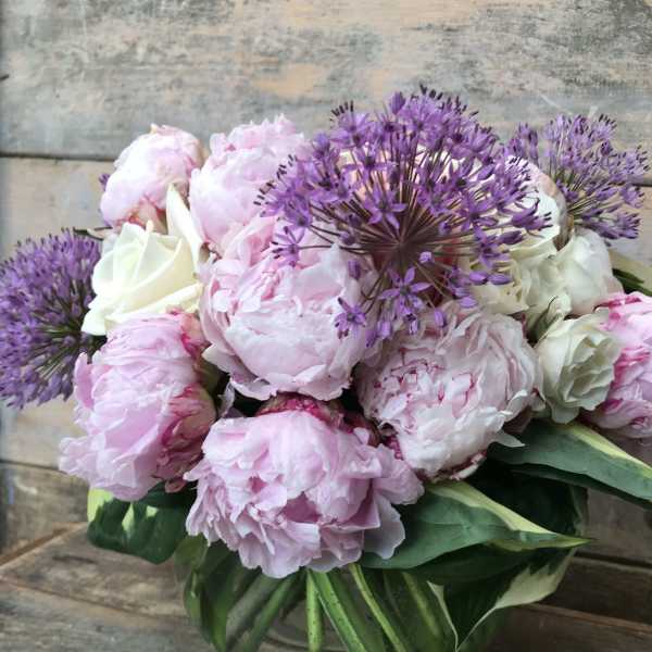 Pink peonies and purple allium in a glass vase