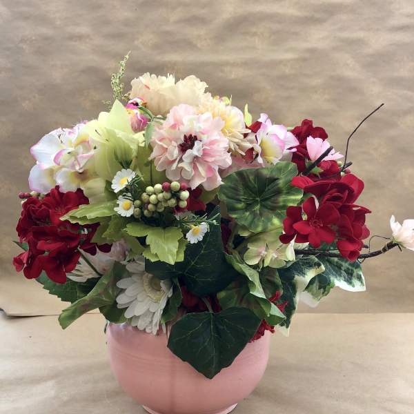 Mixed pink, red, and white flowers arranged in a pink vase