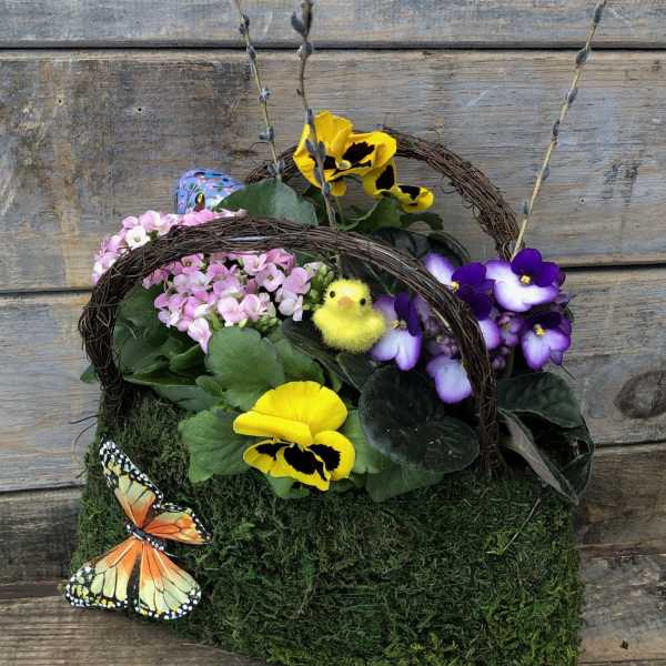 Basket arrangement with yellow and purple pansies, pink flowers, and decorative butterflies