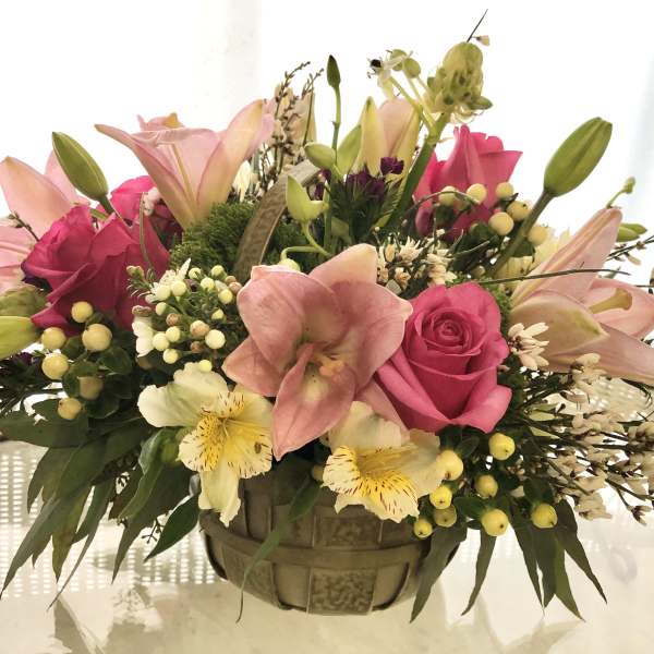 Pink lilies and roses arranged in a woven basket