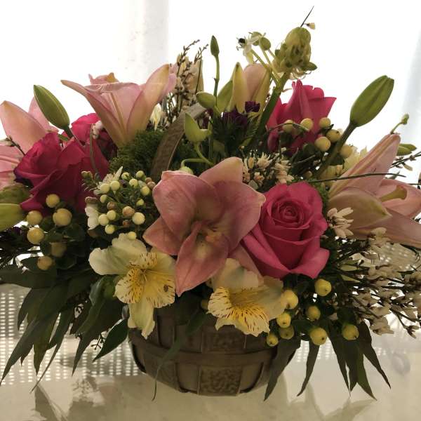 Pink lilies and roses in a basket arrangement