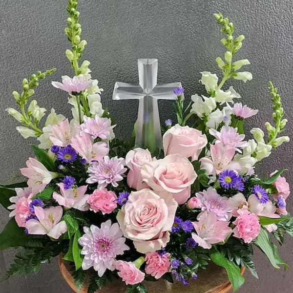 Pink and white floral arrangement with a silver cross centerpiece