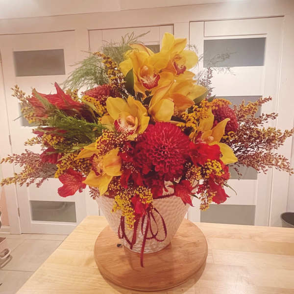Large bouquet of yellow orchids and red flowers in a white vase