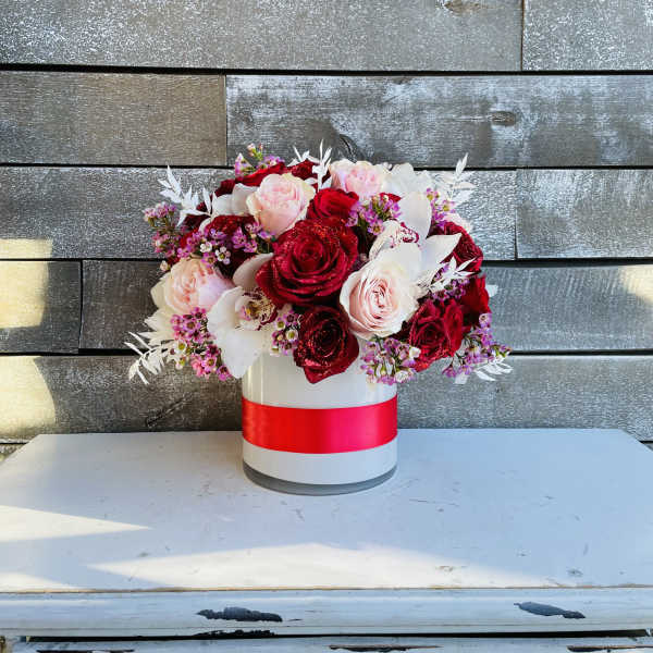 Bouquet of red and blush roses in a white hat box with a red ribbon