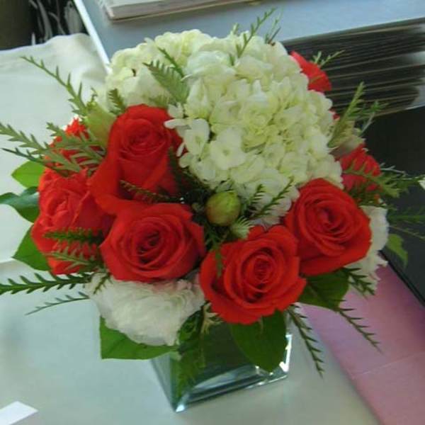 Red roses and white hydrangeas in a clear glass vase