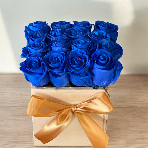 Blue roses in a wooden box with a gold ribbon