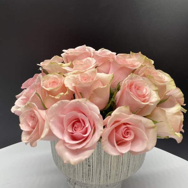 Pink roses arranged in a textured white vase