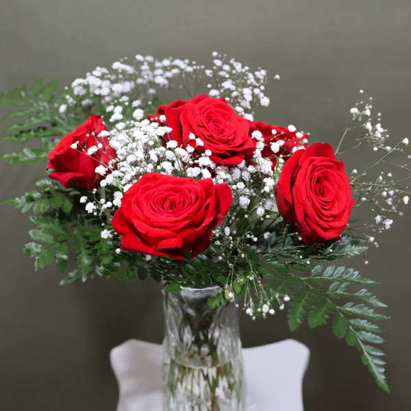 Red roses with white baby's breath in a clear glass vase