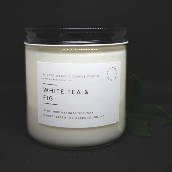 White candle in a glass jar with a black lid and label