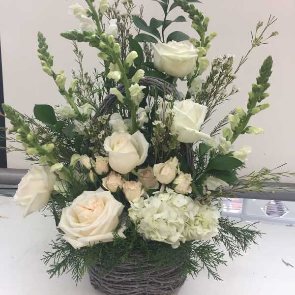 White roses and snapdragons arranged in a wicker basket