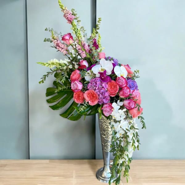 Tall bouquet of pink and white flowers in a silver vase
