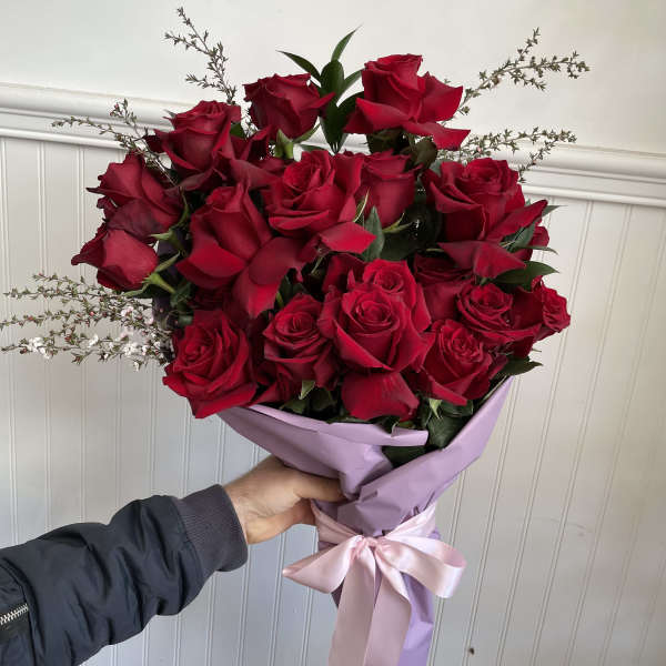 Bouquet of red roses wrapped in lavender paper with a pink ribbon