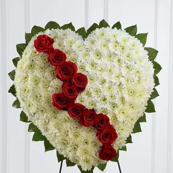 Heart-shaped white floral spray with red roses on a stand