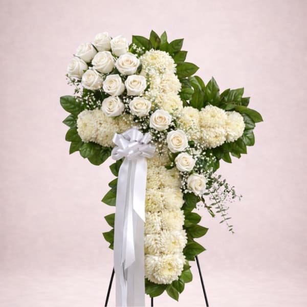 White rose and chrysanthemum cross on a stand with a white ribbon