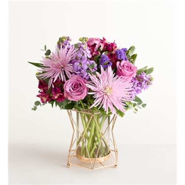 Pink and purple bouquet in a clear glass vase with a gold stand