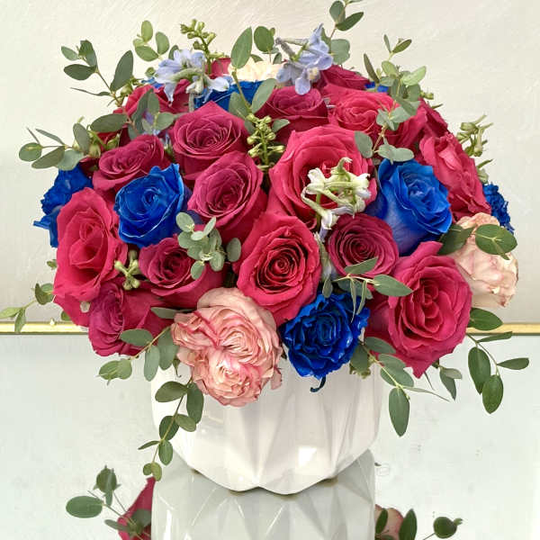 Bouquet of pink, blue, and blush roses in a white vase