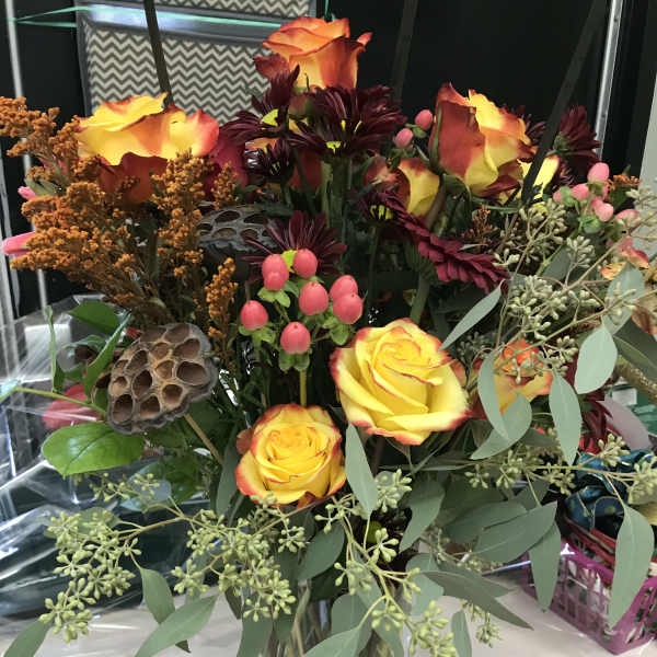 Bouquet of yellow-orange roses in a glass vase with burgundy flowers