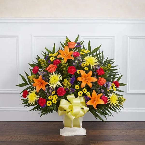 Colorful floral spray in a white basket with a yellow bow