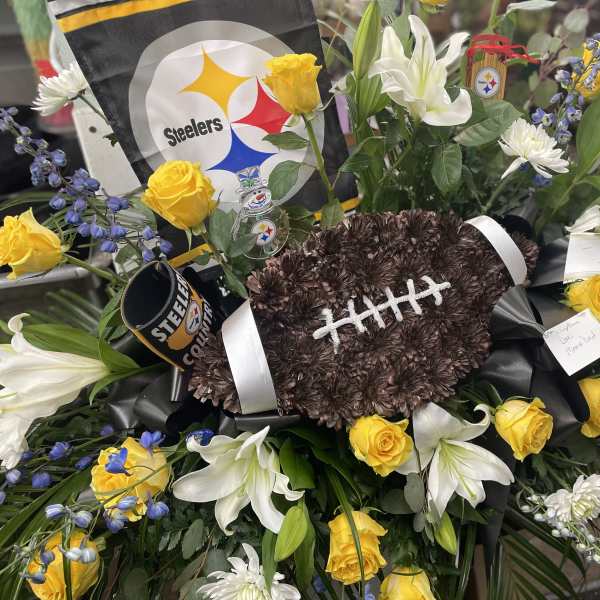 Football-shaped floral tribute with yellow roses and white lilies