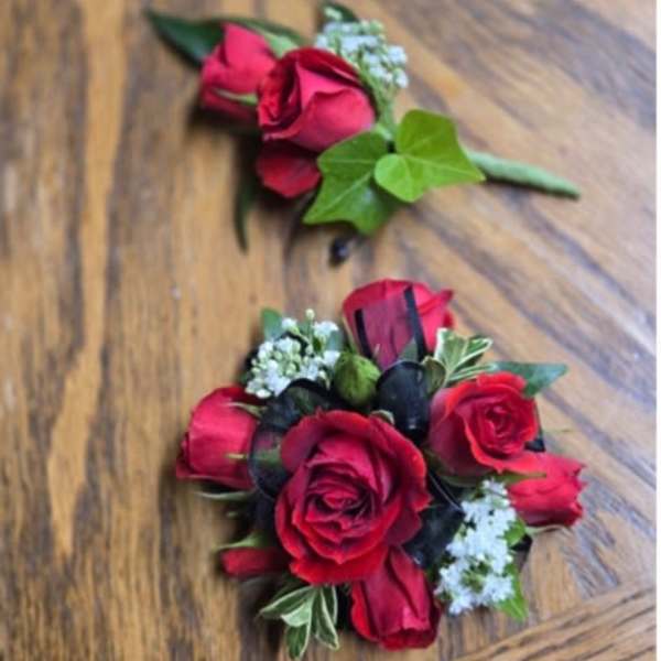 Two red rose boutonnieres with small white filler flowers