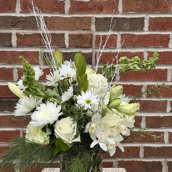 White flowers arranged in a glass vase with greenery and branches