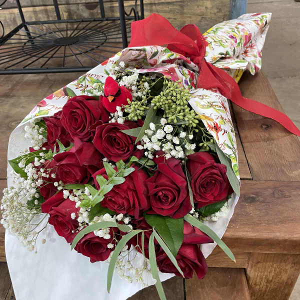 Bouquet of red roses with baby's breath wrapped in floral paper and tied with a red ribbon