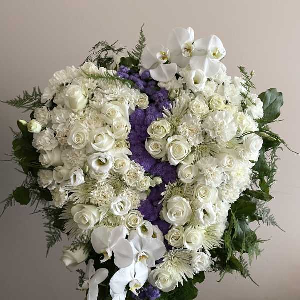 Large white funeral spray with roses and orchids on a stand