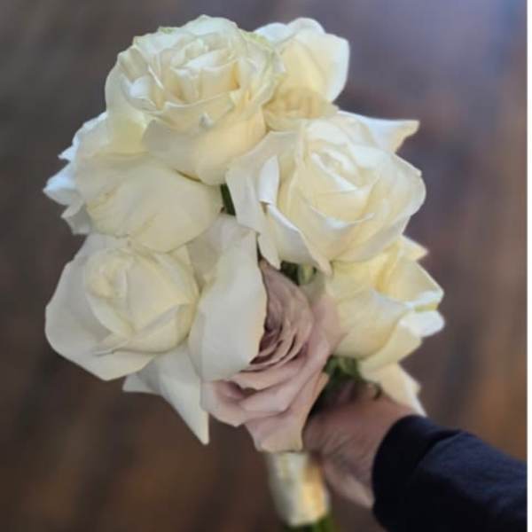 Handheld bouquet of white roses with a pale blush rose