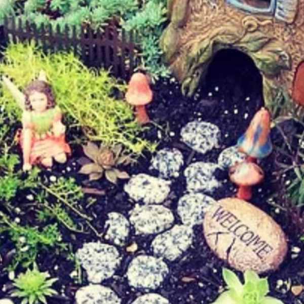 Miniature fairy garden with a tiny house, stepping stones, and small figurines