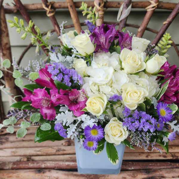 Bouquet of white and purple flowers in a light blue vase