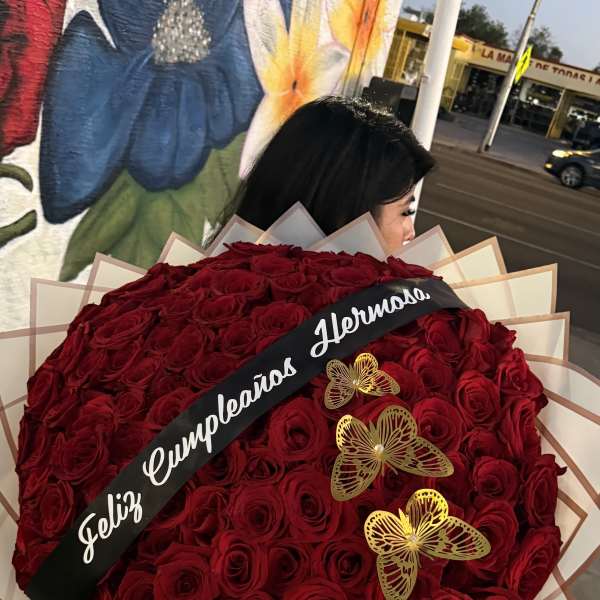 Large bouquet of red roses with a black ribbon and gold butterfly accents