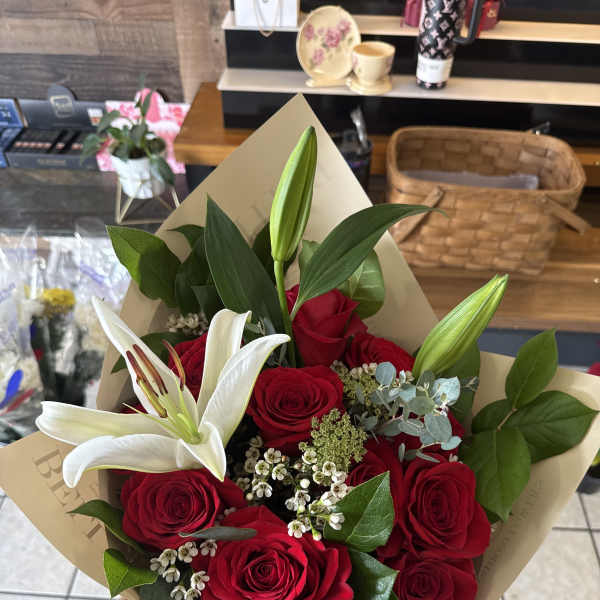 Bouquet of red roses and white lilies wrapped in beige paper