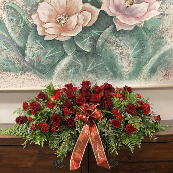 Red rose casket spray with a red ribbon bow