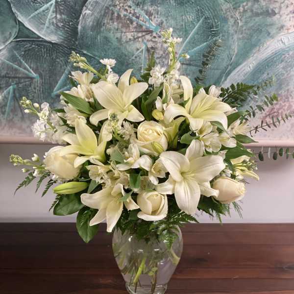 Cream-colored flowers arranged in a clear glass vase