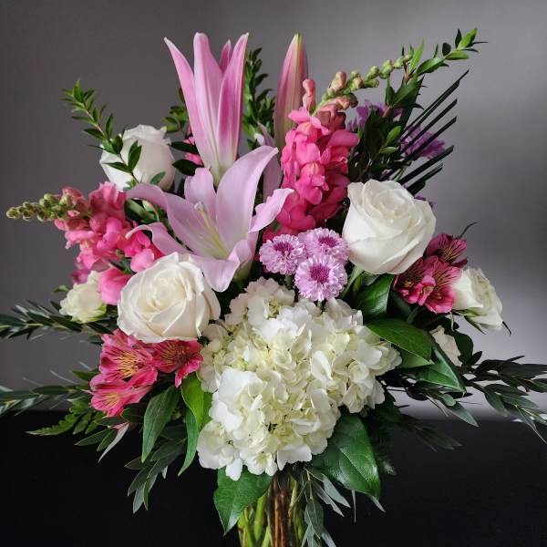 Pink lilies, white roses, and hydrangeas in a glass vase
