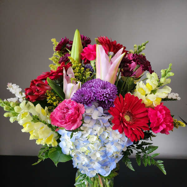 Mixed bouquet in a glass vase with pink, purple, red, and yellow flowers