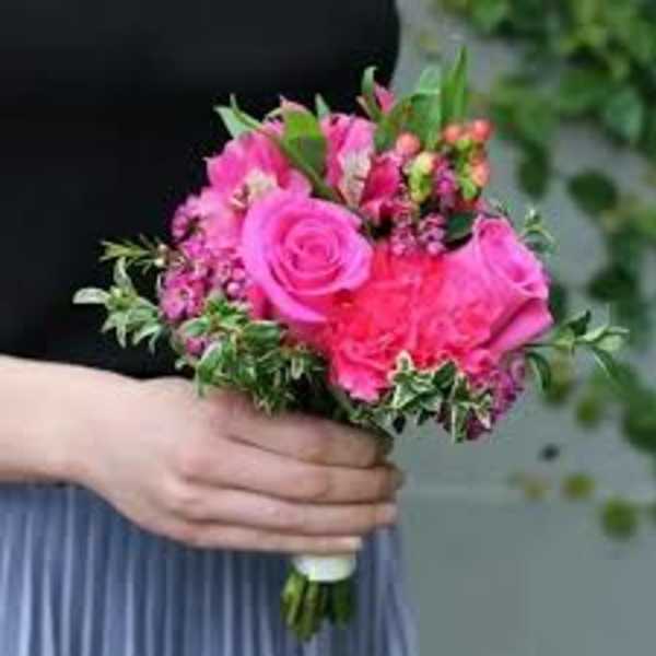Handheld bouquet of pink roses and mixed blooms with greenery