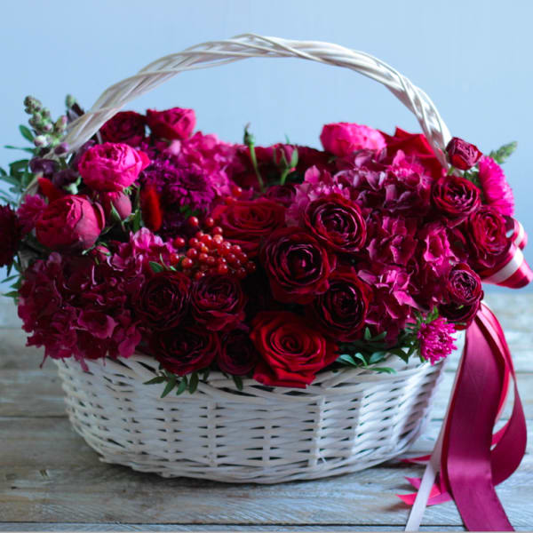 Basket of red and pink roses with hydrangeas and ribbon