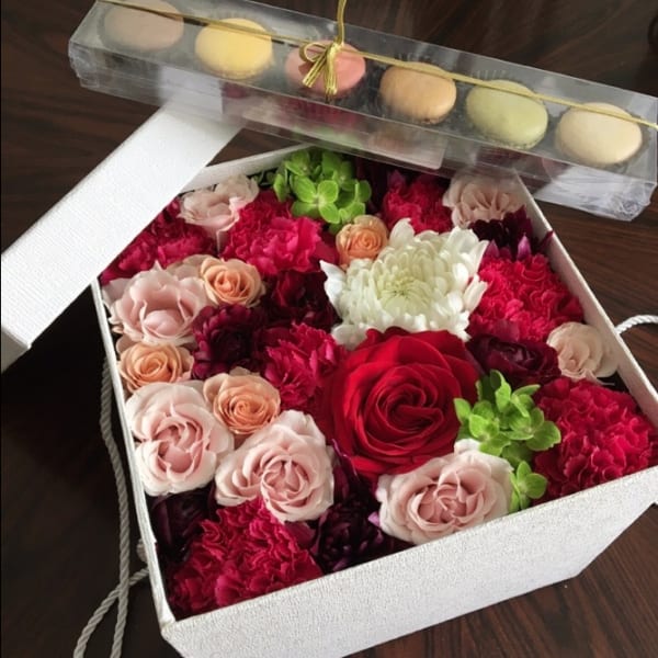 Box of mixed roses and carnations with macarons on top