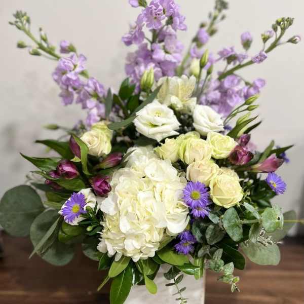 White and lavender floral arrangement in a square vase