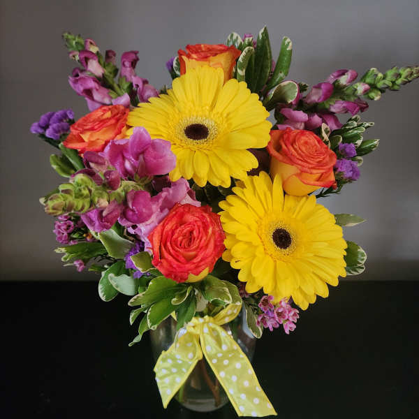 Bouquet of yellow gerbera daisies and orange roses in a glass vase