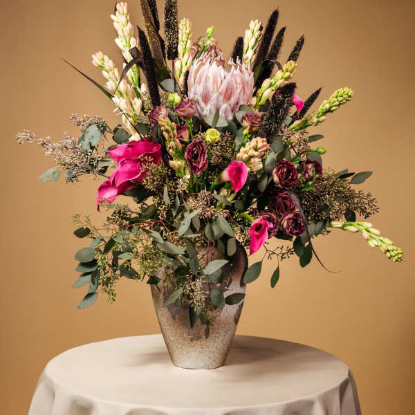 Tall floral arrangement in a textured vase with pink and white blooms