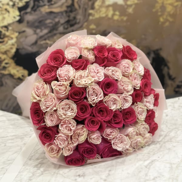 Bouquet of pink and deep red roses wrapped in pale pink paper