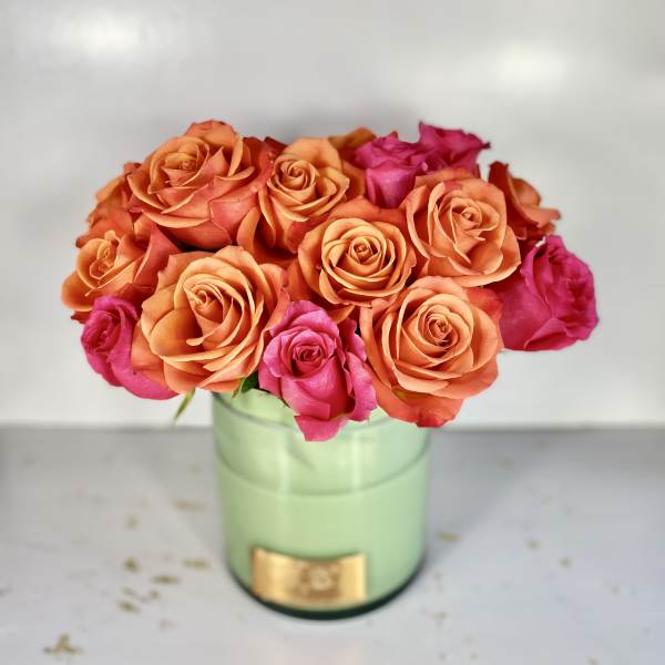 Orange and pink roses arranged in a light green vase